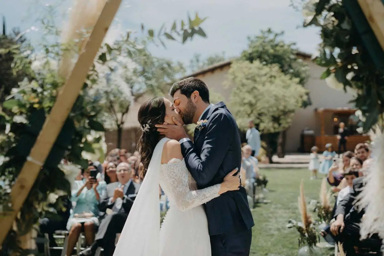 Novios compartiendo su primer beso en una boda en Can Macià